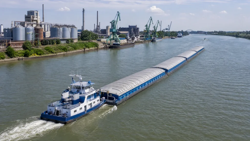 Schubverband auf dem Rhein vor einem Industriehafen aus der Luft